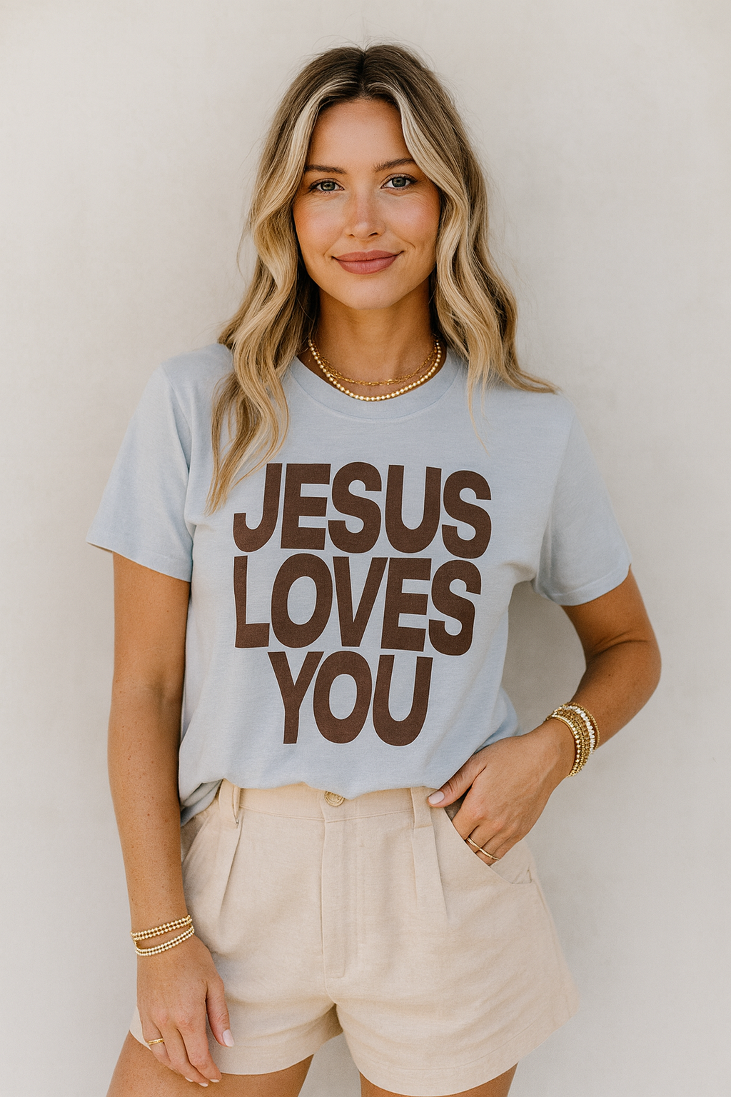 Woman wearing a light blue t-shirt with 'Jesus Loves You' text against a plain background
