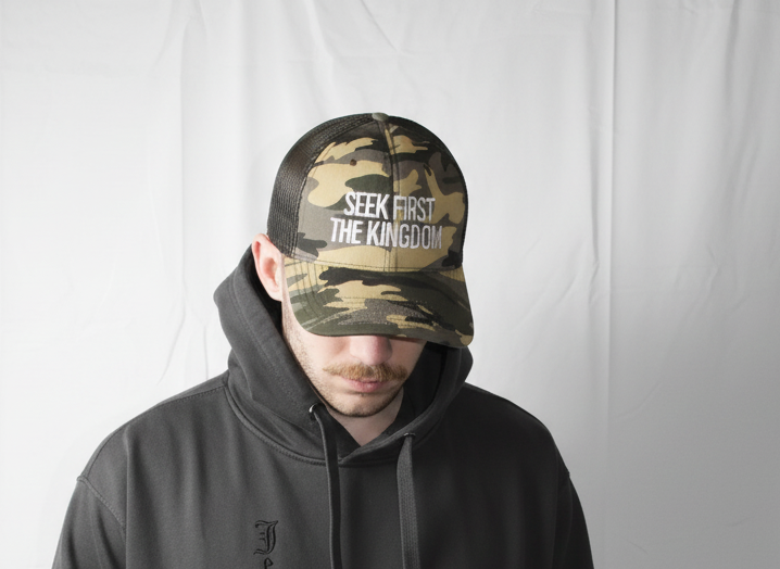 Person wearing a black hoodie and camouflage cap with text on a white background