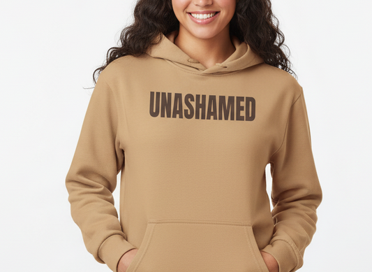 Person wearing a beige hoodie with 'UNASHAMED' text on a white background