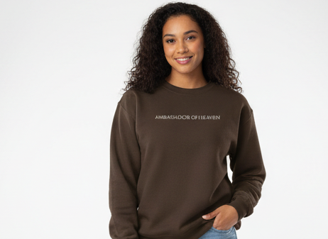 Woman wearing a brown sweatshirt with text in a studio setting with lighting equipment.