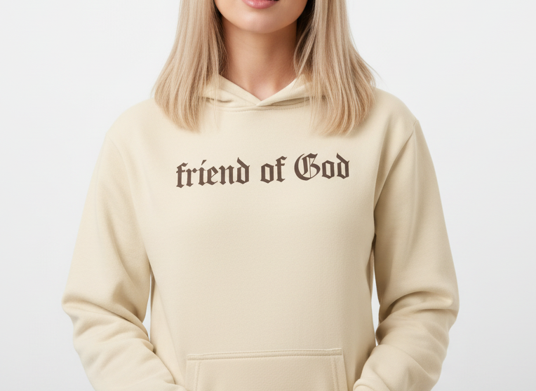 Woman wearing a beige hoodie with 'friend of God' text on a white background